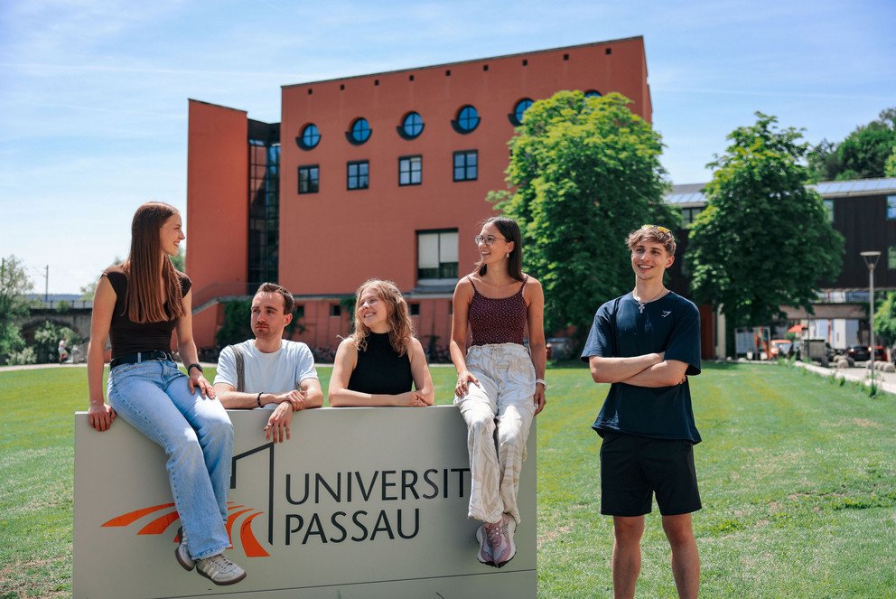 Studierende vor dem Campuslogo der Universit&auml;t Passau; Foto: Universit&auml;t Passau.