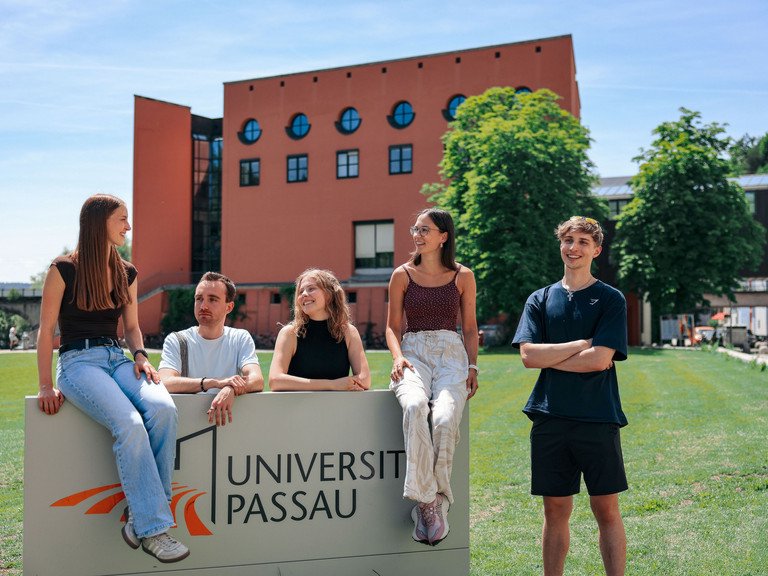 Studierende vor dem Campuslogo der Universit&auml;t Passau; Foto: Universit&auml;t Passau.