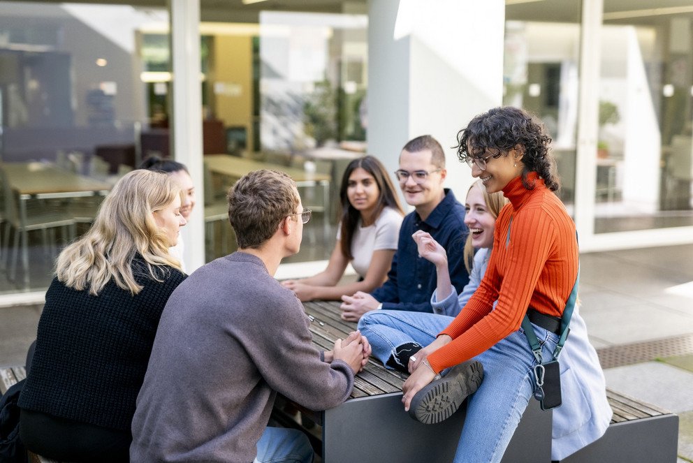 Studierende sitzen auf Bank vor ZMK Foto: Universit&auml;t Passau