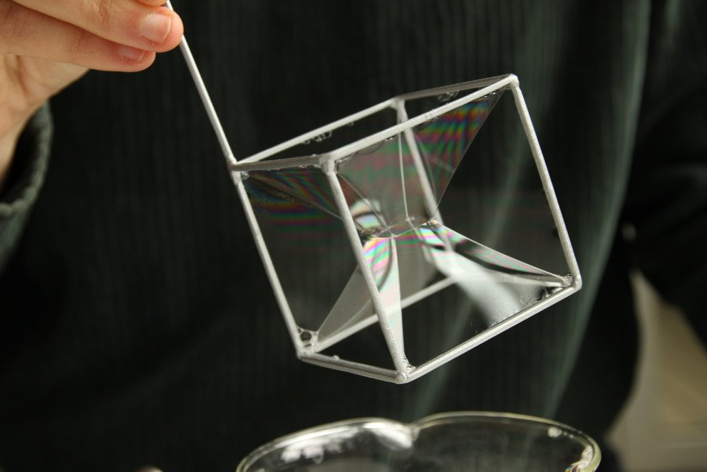 Metall-Skelett eines W&uuml;rfels mit Seifenblasenkonstellation darin. Titel: Minimalfl&auml;chen