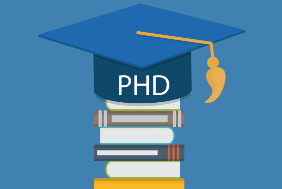 ein akademischer Hut mit der Aufschrift "PhD" liegt auf einem Bücherstapel