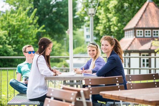 Studierende sitzen an einem Tisch in der Natur