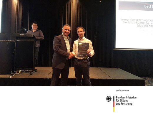Prof. Edmundo Tovar, Universidad Polit&eacute;cnica Madrid und Vice-President der IEEE Education Society, gratuliert dem Passauer Informatikdidaktiker Dengel zum Best-Paper-Award f&uuml;r seinen Beitrag zum Thema Immersive Learning. Im Hintergrund Mark Lee, einer der Organisatoren der Konferenz. Foto: Robert Dongas, Universit&auml;t Passau
