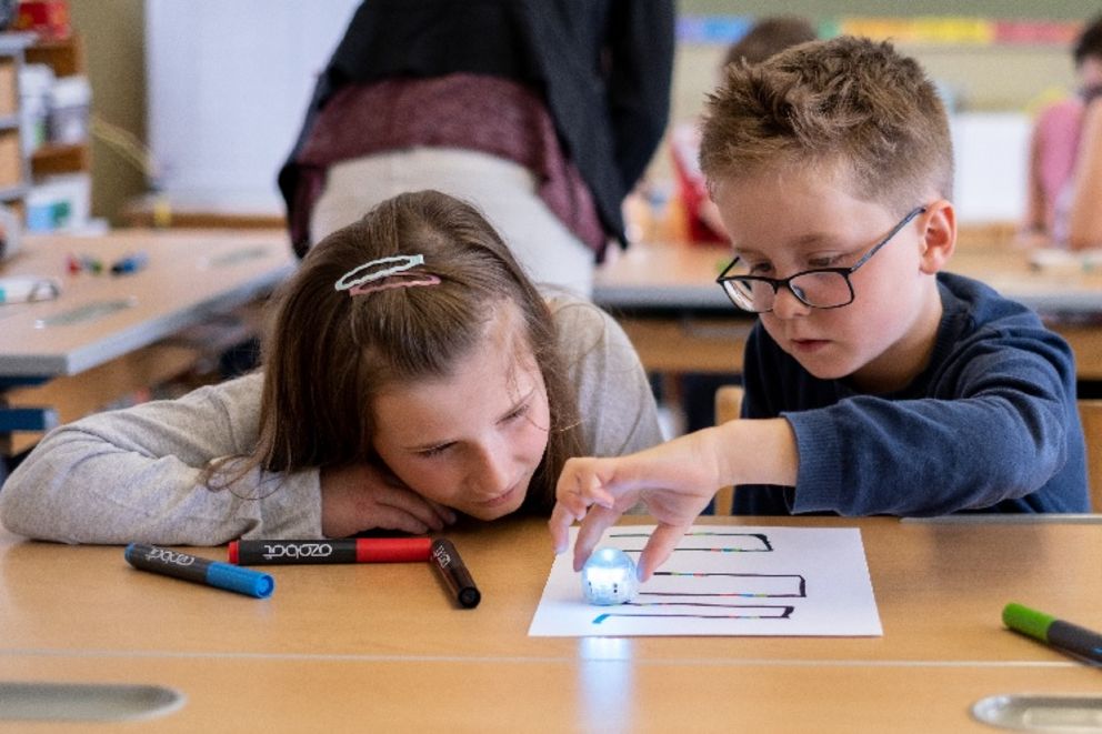 Informatik in der Grundschule: Die Kinder testen den Roboter auf ihrem Blatt Papier.