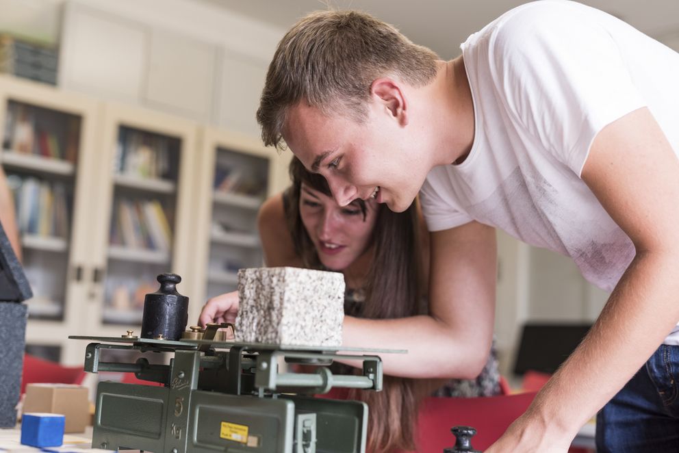 Studierende der Universität Passau untersuchen fasziniert die Funktionsweise einer alten Waage